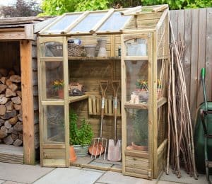 Forest Victorian greenhouse in a garden setting.