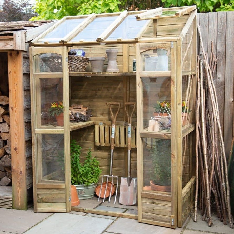 Forest Victorian greenhouse in a garden setting.